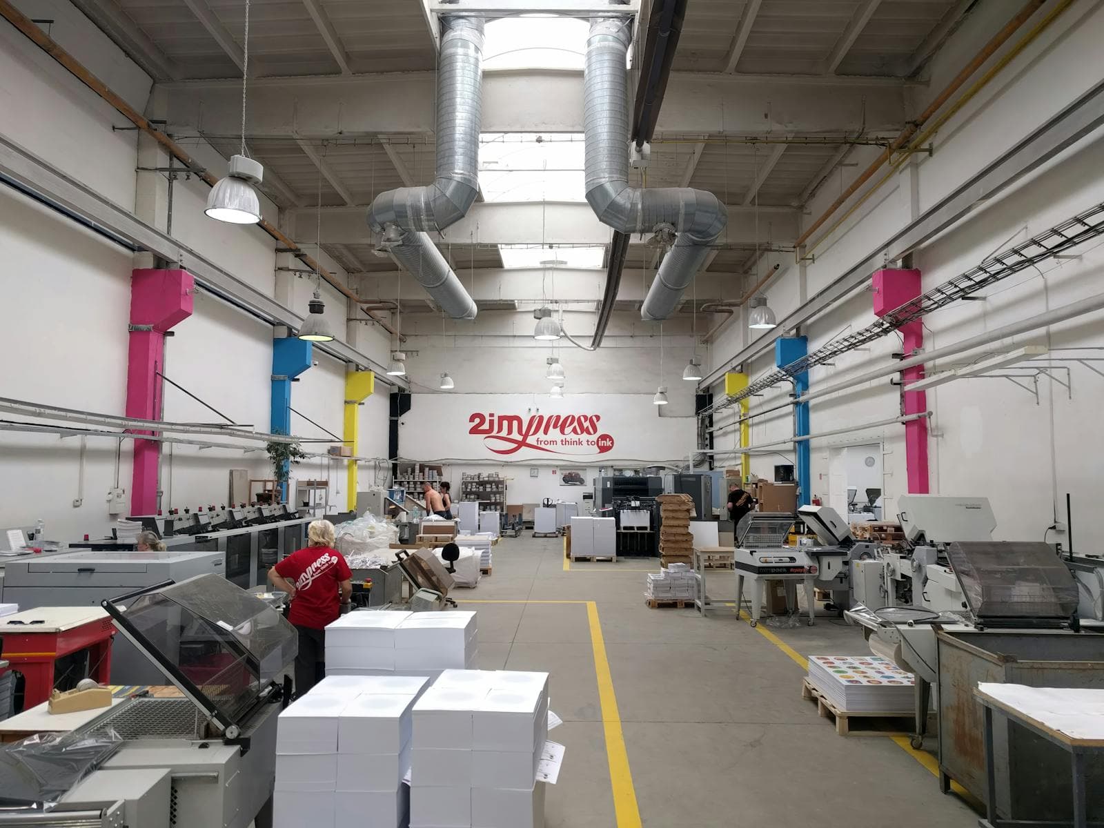 Spacious industrial printing facility interior with modern machinery and workers.