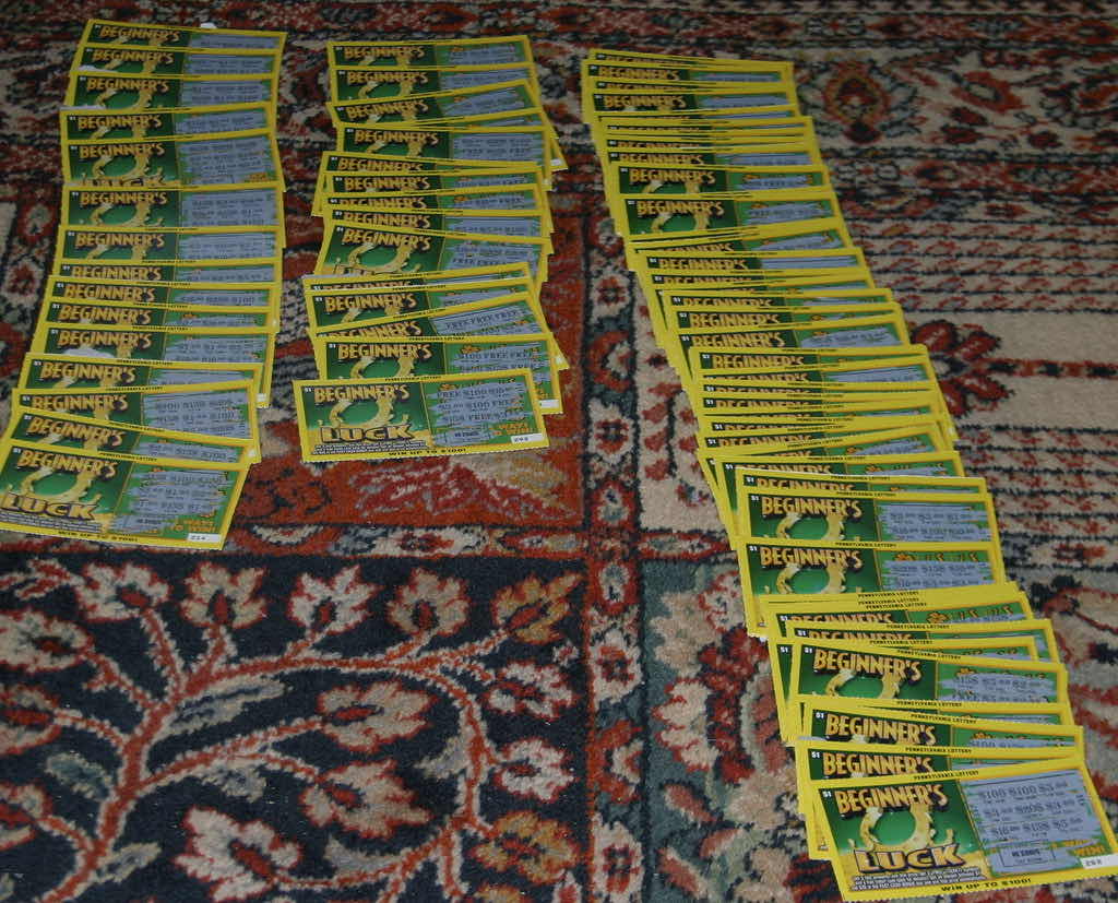 About one hundred scratched one-dollar Pennsylvania Lottery Beginner's Luck tickets laid out in rows on a carpet.